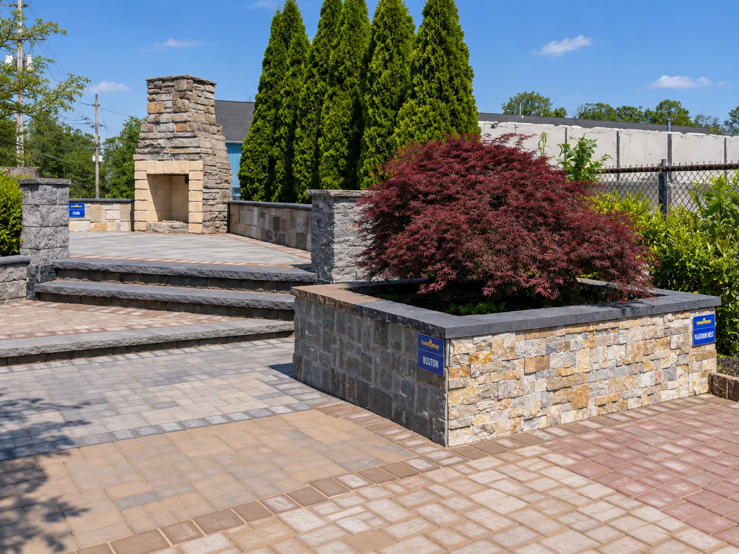 Outdoor hardscape display with paved steps, stone walls, a fireplace and a Japanese maple